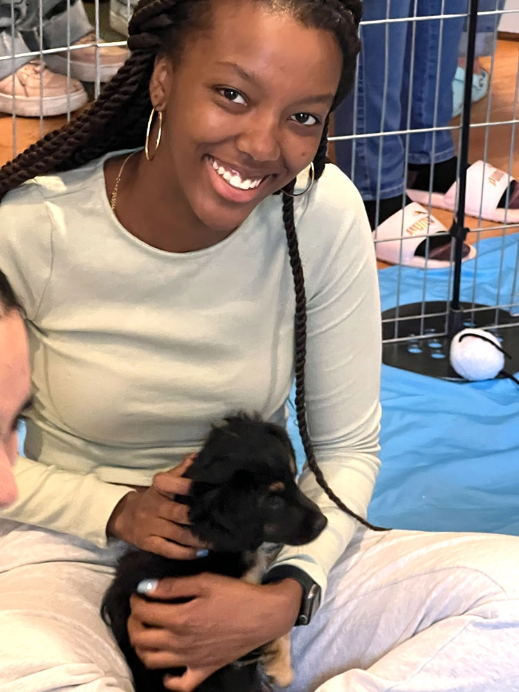 A girl holding a black puppy - puppy love™ is the best workplace wellness ideas.