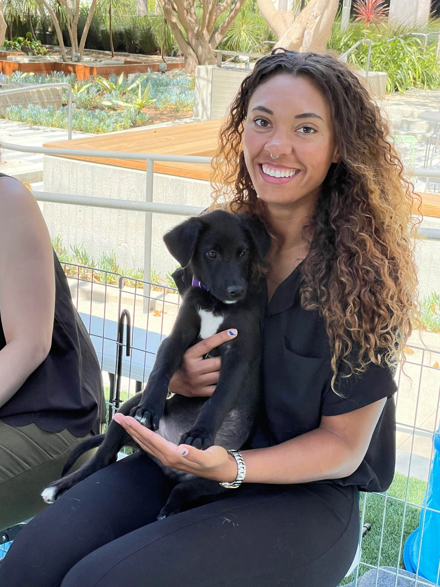 A girl holding a puppy thats making her feel happy at a event with puppy love™.