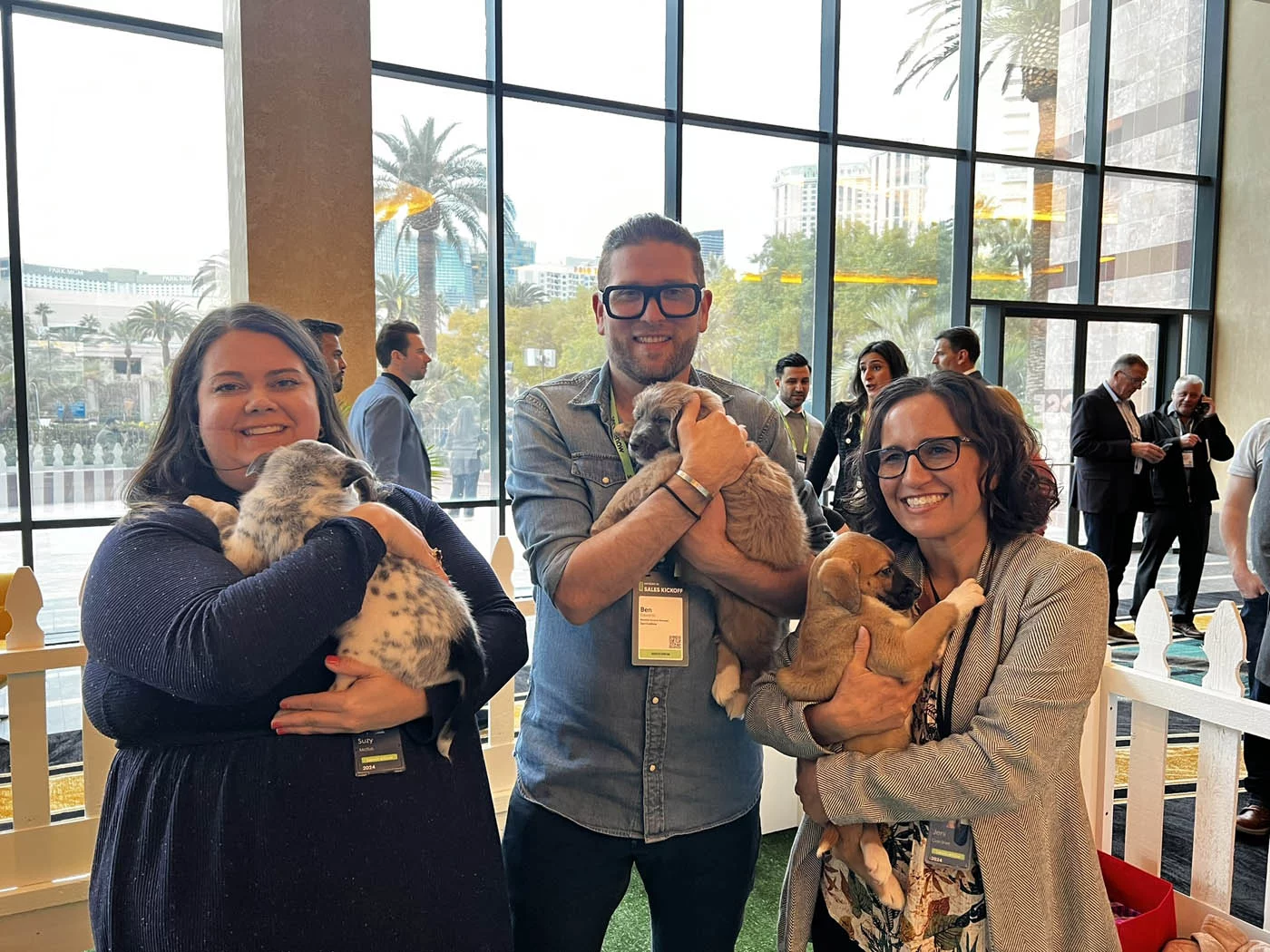 A group of people holding adorable puppies and feeling the benefits of puppy love™ added to their company wellness programs.