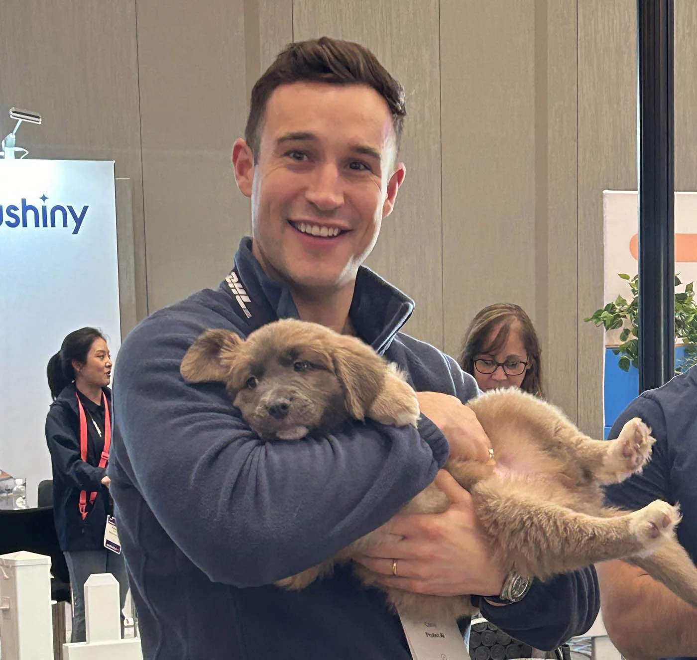 Manifest 77 Puppy love™ man holding puppy at manifest 2024 conference