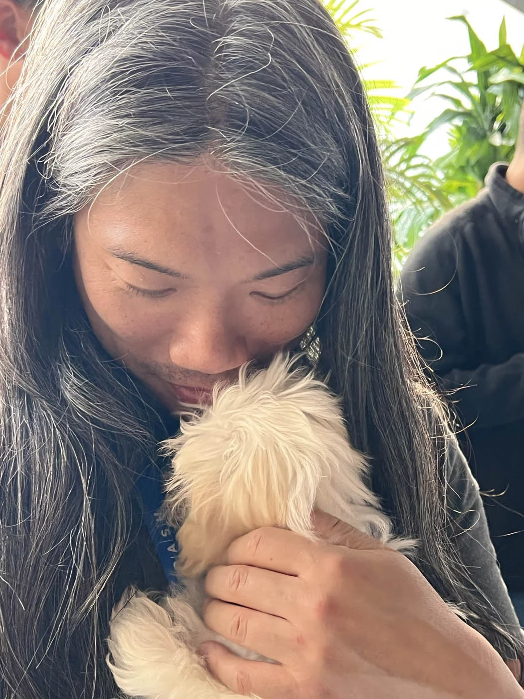 A guy snuggling a puppy at a puppy love™ puppy experience - we create wellness in companies.