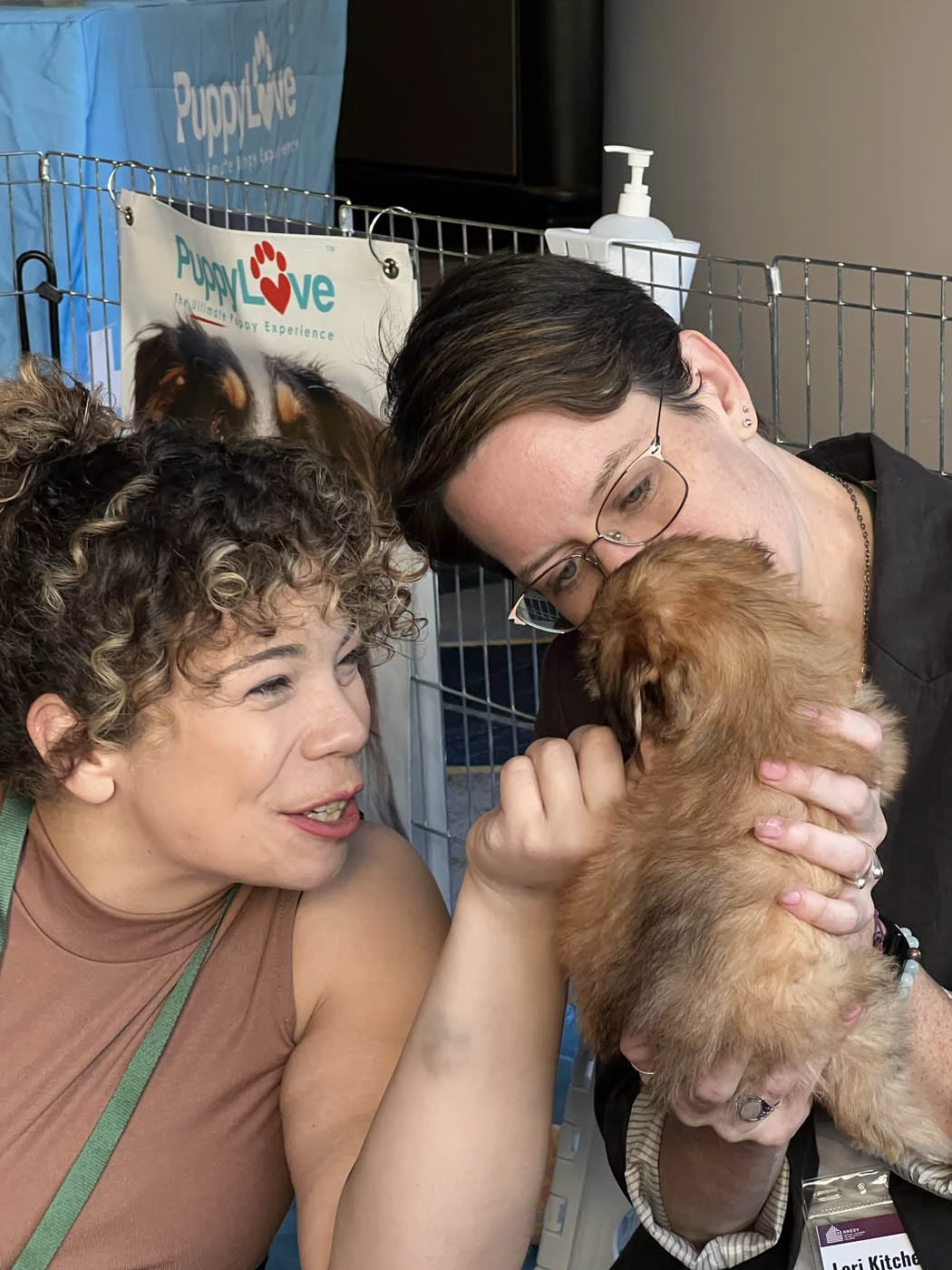 Two people holding puppies and enjoying the wellness in companies that puppy love™ provides.