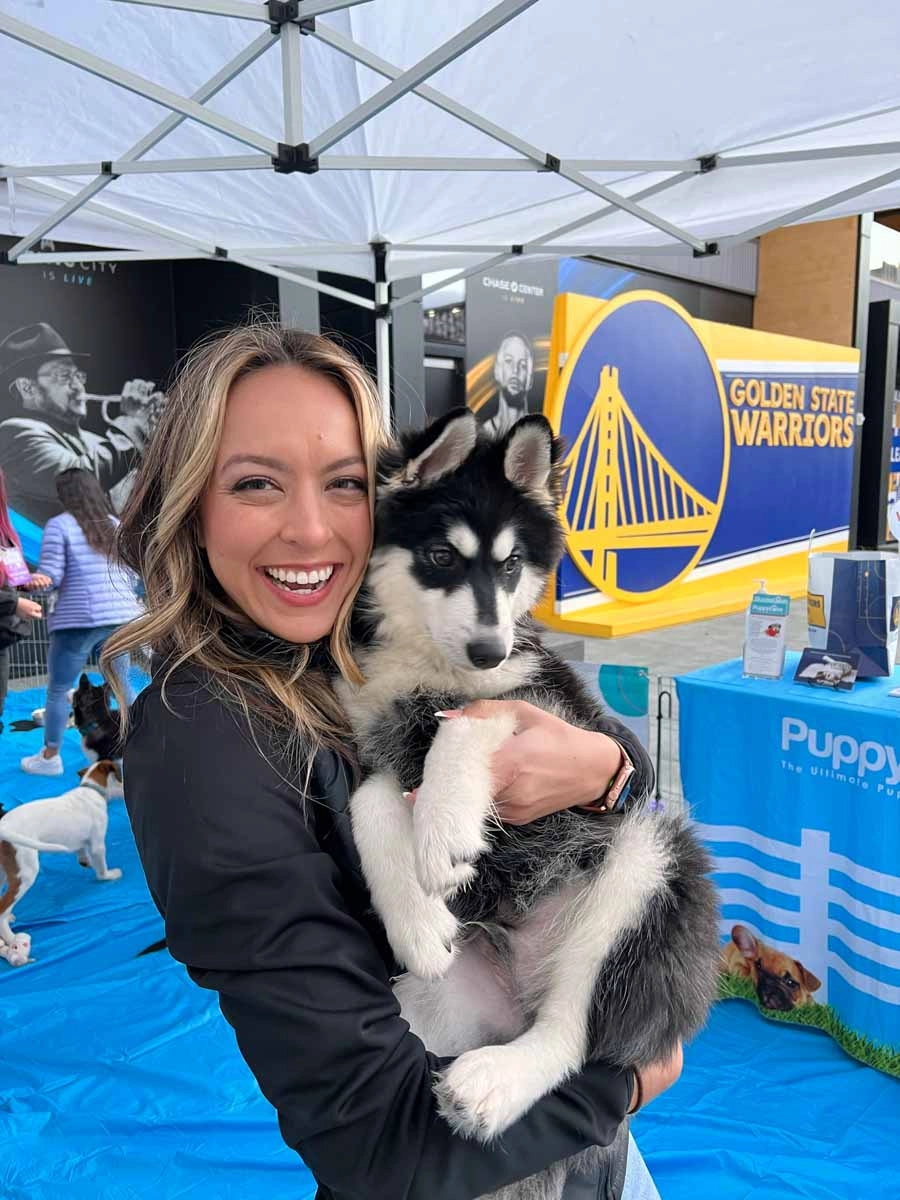 A person holding an adorable puppy at a community sports and wellness center.
