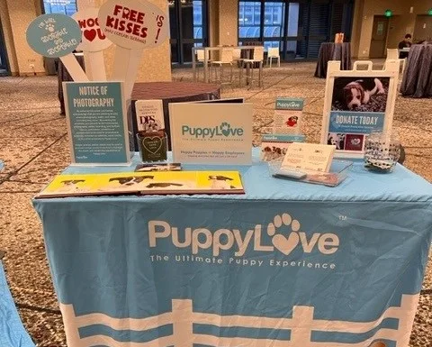 Puppy love booth with puppy therapy info and donation display.